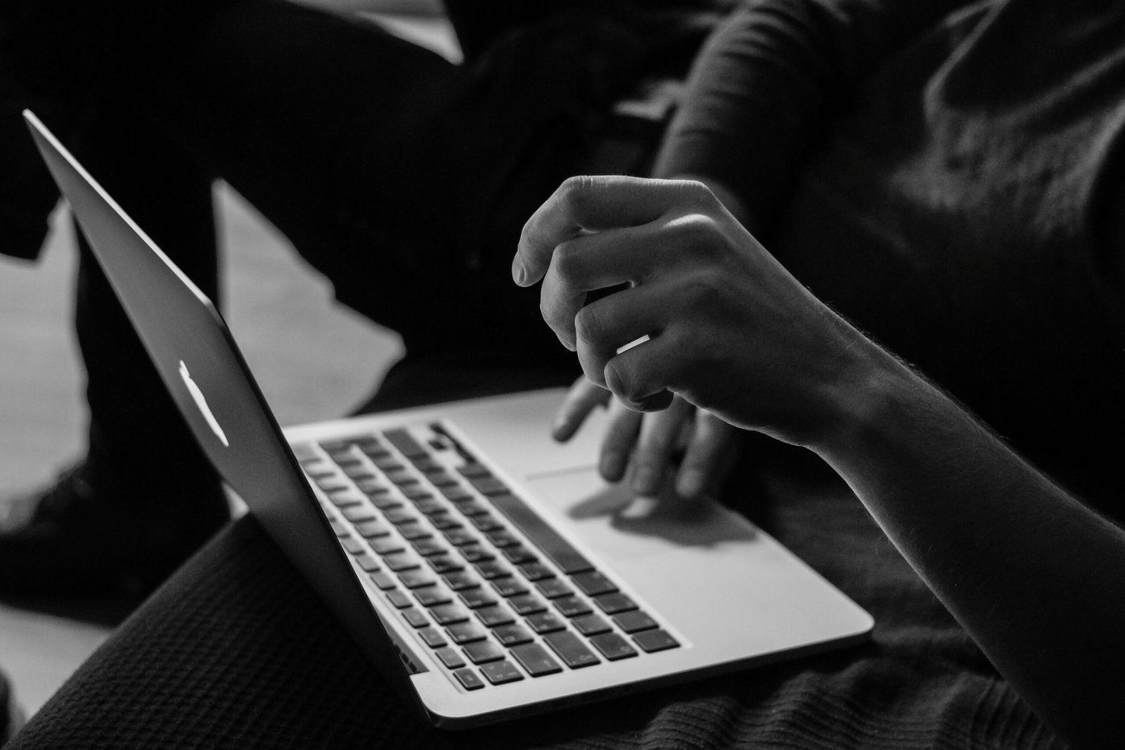 Hände tippen auf der Tastatur eines aufgeklappten Laptops