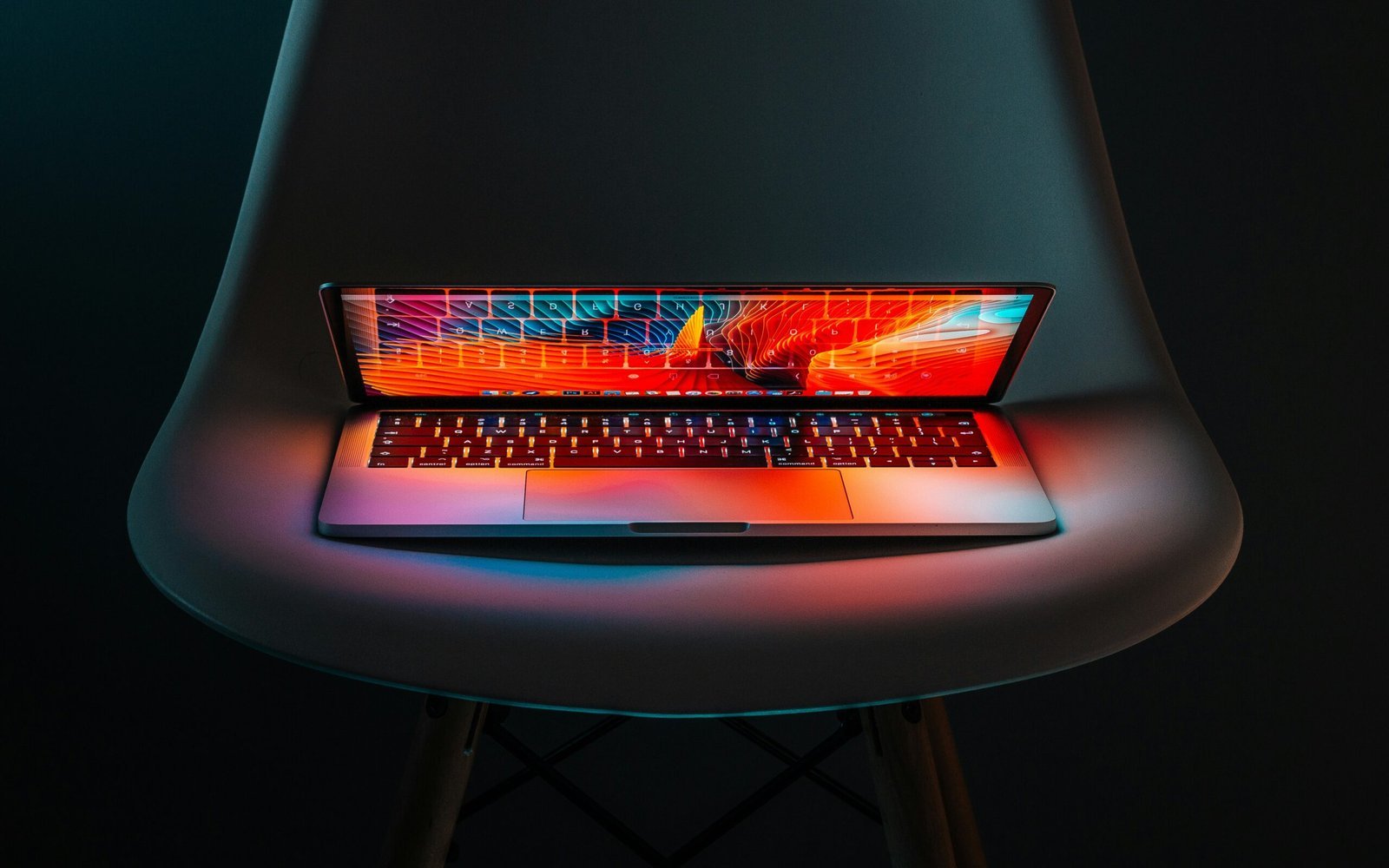 Laptop mit farbig leuchtendem Bildschirm auf einem hellen Stuhl